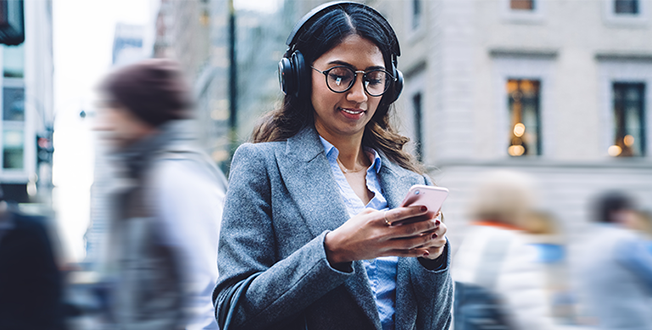 Woman using phone in the street while wearing headphones
